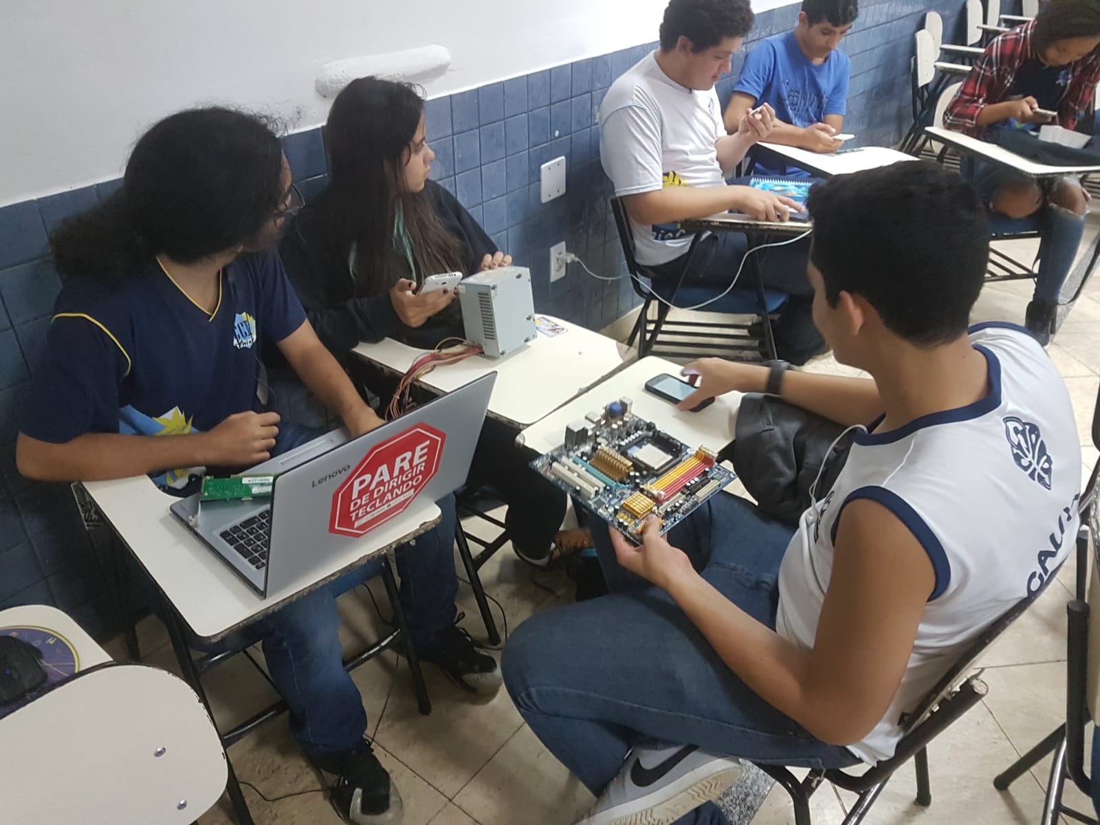 Mentor acompanhando construtores em atividade prática com hardware em sala